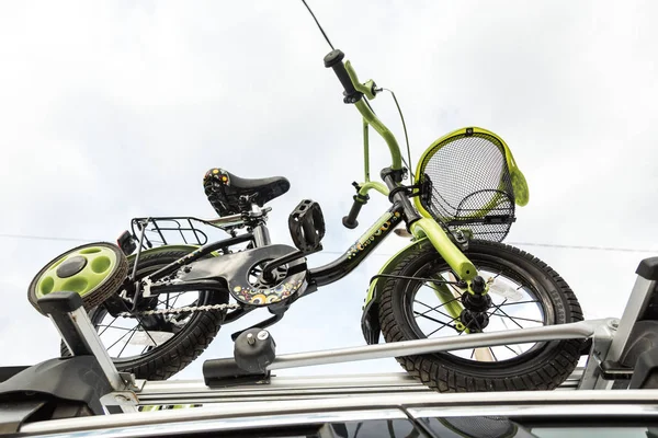 自転車輸送 - サイクリングのための特別なマウントで空に対して車の屋根の上に子供の自転車。大きな荷物を輸送し、車で旅行する決定 — ストック写真