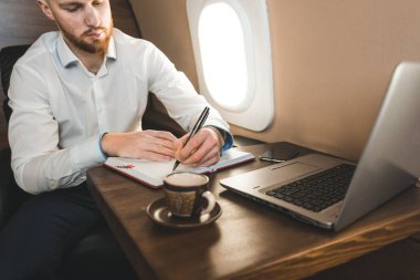 Beyaz gömlekli çekici ve başarılı bir iş adamı özel jetinin koltuğunda oturuyor..