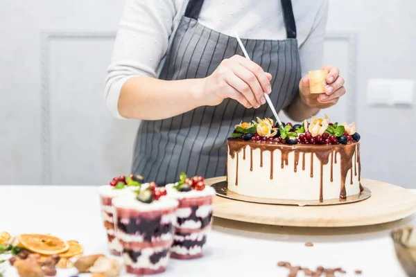 Decoratie van het afgewerkte dessert. Banketbakker bestrooit zoetwaren met geel poeder. Het concept van zelfgemaakte gebak, koken cakes. — Stockfoto