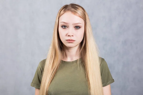 Retrato de una joven y hermosa mujer triste sobre un fondo gris . — Foto de Stock