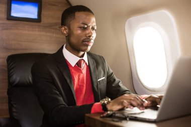 Onun özel jet sandalyede otururken gözlük bir dizüstü bilgisayar üzerinde çalışan çekici ve başarılı Afrikalı Amerikan işadamı