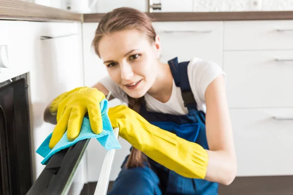 Úklidová služba s profesionálním vybavením během práce. profesionální úklid kuchyňky, chemické čištění pohovky, mytí oken a podlah. muž a ženy v uniformách, kombinézách a gumových rukavicích — Stock fotografie