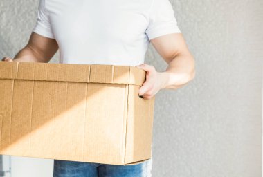 Bir daireye taşınmak için karton kutuları yükleyen güçlü, kaslı bir adam. Profesyonel ulaşım işçisi, tulumlu erkek yükleyiciler. Metin için boş alan, izole edilmiş