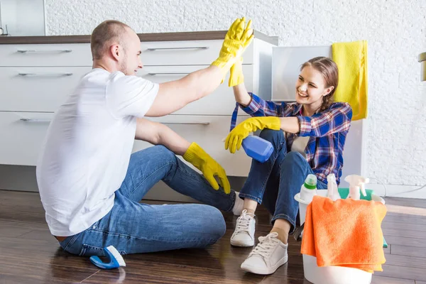 Young couple husband and wife do the house cleaning. The guy and the girl wash the kitchen with a mop and cloth, teamwork, fun — Stock Photo, Image