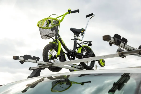 Bicycle transportation - a childrens bicycle on the roof of a car against the sky in a special mount for cycling. The decision to transport large loads and travel by car
