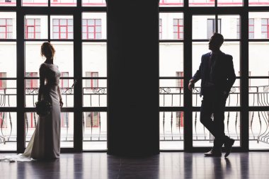 şık bir boş iç büyük bir panoramik vitray pencere yakınında birbirlerine bakan çiçek bir buket ile takım elbise li bir adam ve bir kadın ışık gölge siluetleri