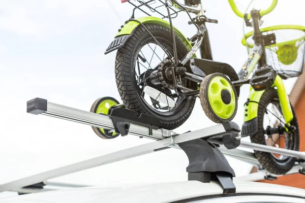 Transport à vélo - un vélo pour enfants sur le toit d'une voiture contre le ciel dans une monture spéciale pour le vélo. La décision de transporter de gros chargements et de voyager en voiture — Photo