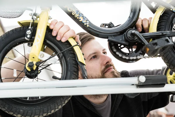Cykeltransport-en man fäster och installerar en barnens cykel på taket av en bil i ett speciellt fäste för cykeltransport. Beslutet att transportera stora laster och resa med bil. — Stockfoto