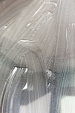 Üniformalı ve sarı eldivenli bir kadının yakın çekimi pencere kazıyıcıile camyı yıkar. Profesyonel ev temizliği