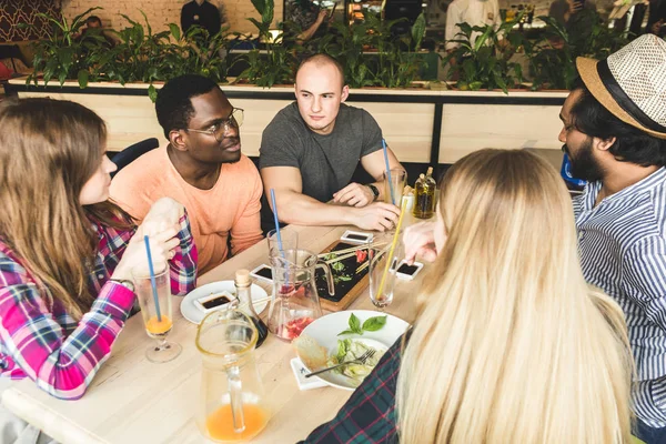 Meet young attractive people in the cafe. Friends chat, have fun, drink cocktails and eat