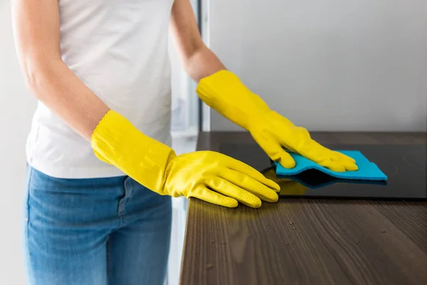 Молодая женщина из профессиональной компании по уборке убирается дома. Мужчина моет кухню в жёлтых перчатках с моющими средствами. . — стоковое фото