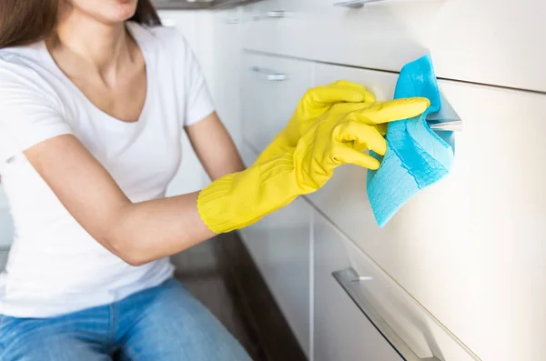 Eine junge Frau von einer professionellen Reinigungsfirma räumt zu Hause auf. Ein Mann wäscht die Küche in gelben Handschuhen mit Putzmitteln. — Stockfoto