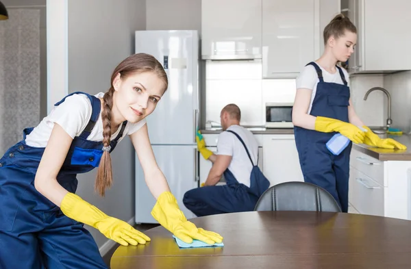 Cleaning service with professional equipment during work. professional kitchenette cleaning, sofa dry cleaning, window and floor washing. man and women in uniform, overalls and rubber gloves