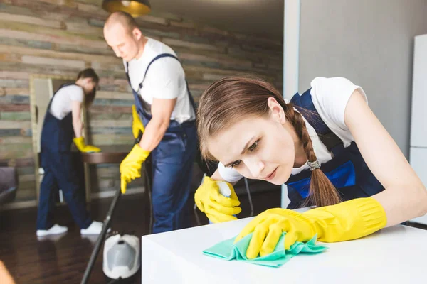 Serviço de limpeza com equipamento profissional durante o trabalho. limpeza kitchenette profissional, sofá limpeza a seco, janela e lavagem de piso. homem e mulher de uniforme, macacão e luvas de borracha — Fotografia de Stock