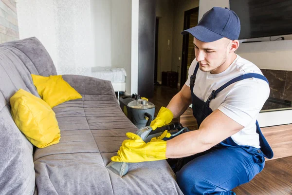 Servizio di pulizia con attrezzature professionali durante il lavoro. pulizia professionale angolo cottura, divano lavaggio a secco, finestra e pavimento. uomo e donna in uniforme, tuta e guanti di gomma — Foto Stock