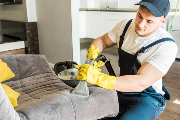 İş sırasında profesyonel ekipmanlarla temizlik hizmeti. Profesyonel mutfak temizliği, kanepe kuru temizleme, pencere ve yer silme. Erkek ve kadın üniformalı, tulumlu ve lastik eldivenli. — Stok fotoğraf