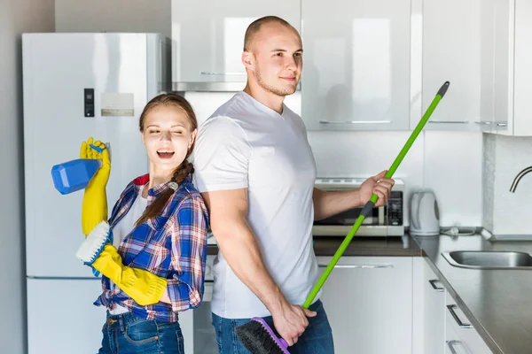 Casal jovem marido e mulher fazer a limpeza da casa. O cara e a menina lavar a cozinha com uma esfregona e pano, trabalho de equipe, diversão — Fotografia de Stock