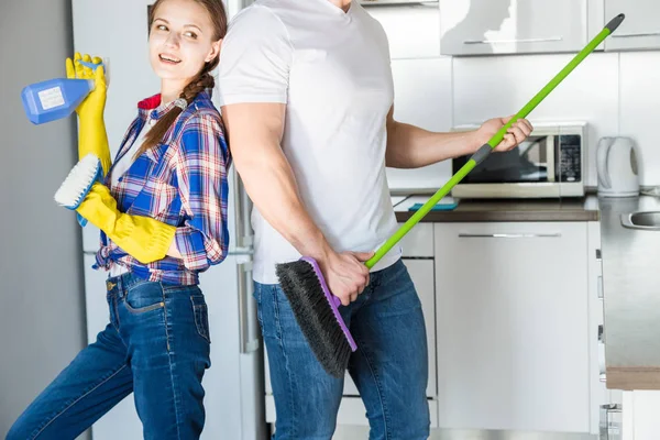 Casal jovem marido e mulher fazer a limpeza da casa. O cara e a menina lavar a cozinha com uma esfregona e pano, trabalho de equipe, diversão — Fotografia de Stock