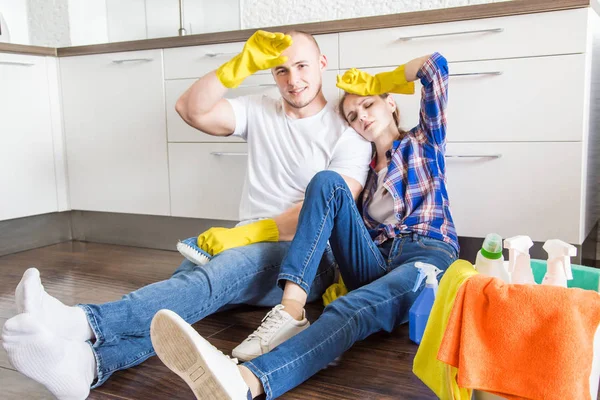 若い夫婦と妻は家の掃除をします。男と女の子はモップと布で台所を洗う,チームワーク,楽しい — ストック写真