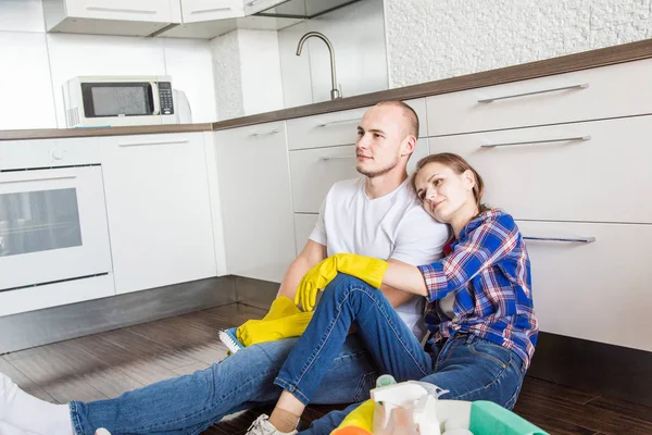 Pareja joven marido y mujer limpian la casa. El chico y la chica lavan la cocina con una fregona y un paño, trabajo en equipo, diversión — Foto de Stock