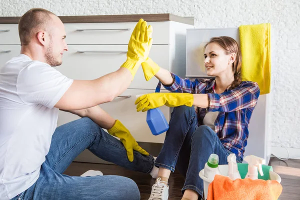 Jong stel man en vrouw doen de schoonmaak. De man en het meisje wassen de keuken met een dweil en doek, teamwork, plezier — Stockfoto