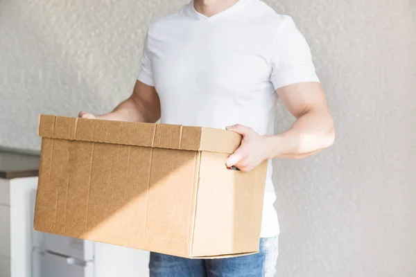 Delivery strong, muscular man loading cardboard boxes for moving to an apartment. professional worker of transportation, male loaders in overalls. free space for text, isolated