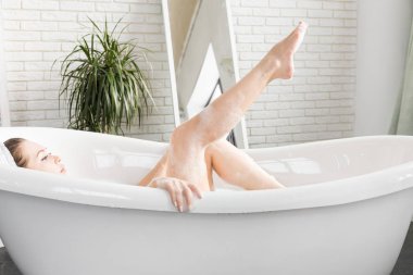 Genç çekici bir kız banyoda rahatlatır ve güzel bir ışık iç zemin karşı oturmaktadır. Cilt Bakımı ile güzellik ve sağlık için spa uygulamaları