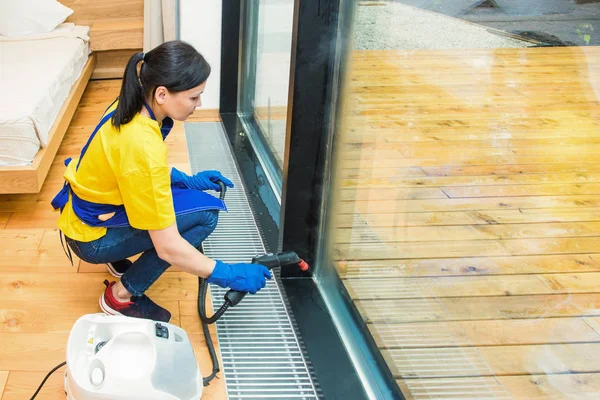 Professionele schoonmaak. vrouw in uniform en handschoenen spons wast panoramische ramen in het huisje. wassen van stoommop en schraper — Stockfoto