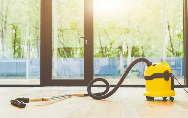 professinal cleaning. yellow vacuum cleaner on wooden floor