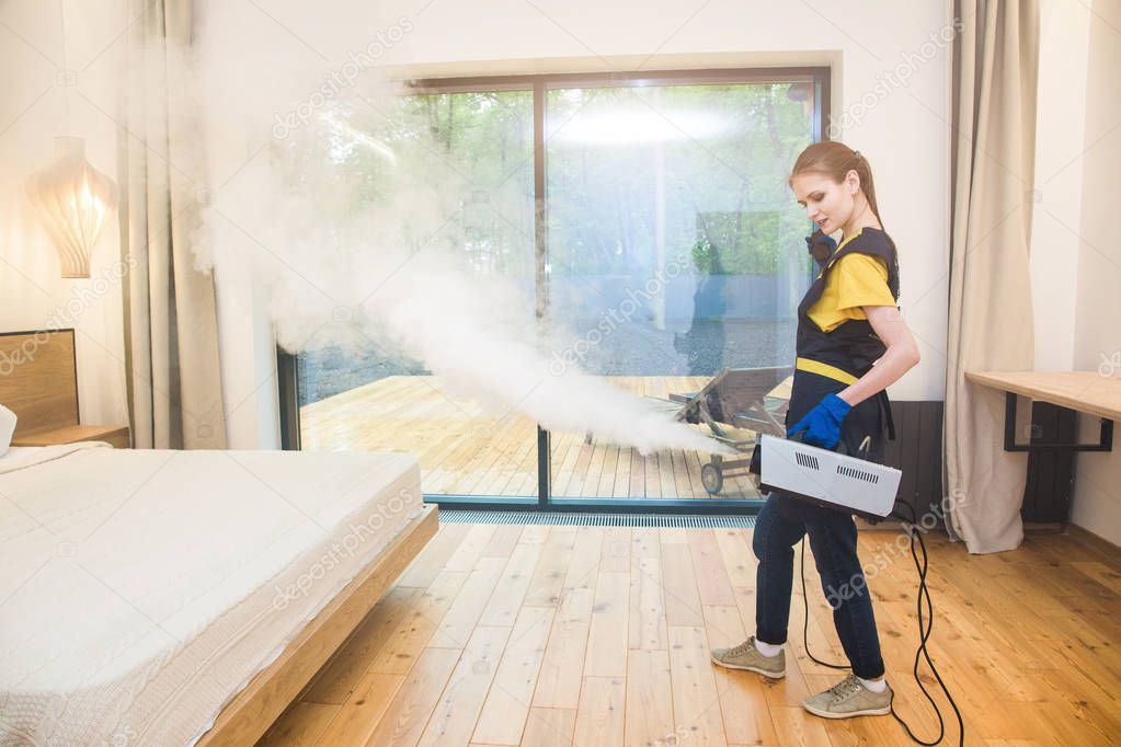 professional cleaning service. woman in uniform and gloves does the cleaning in a cottage. treatment, disinfection of the apartment with hot steam from odors and parasites, bed bugs