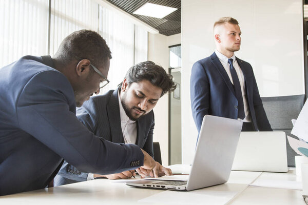 A team of young businessmen working and communicating together in an office. Corporate businessteam and manager in a meeting.