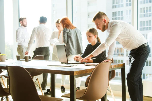 A team of young businessmen working and communicating together in an office. Corporate businessteam and manager in a meeting.