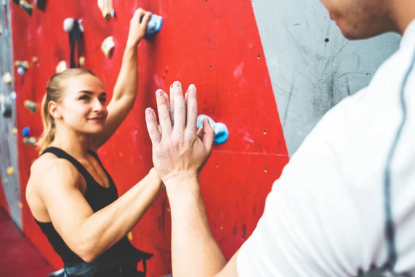 Pareja de atletas escalador ascendiendo en roca escarpada, escalando en la pared artificial en el interior. Concepto de deportes extremos y bouldering — Foto de Stock