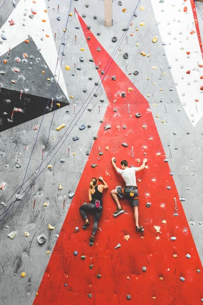 Двое спортсменов поднимаются по крутой скале, взбираются на искусственную стену в помещении. Экстремальные виды спорта и боулдеринг — стоковое фото