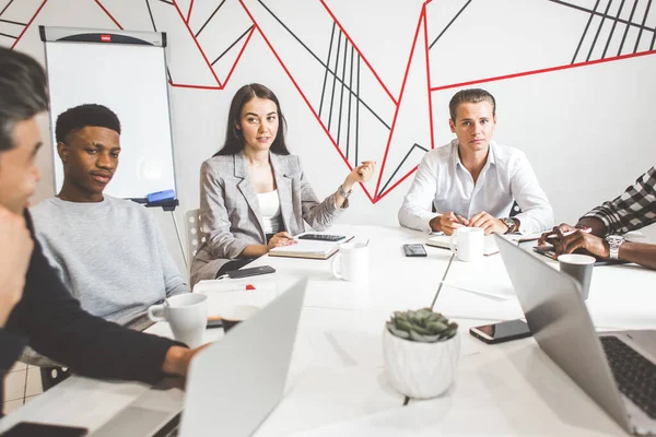 Un equipo de jóvenes trabajadores de oficina, empresarios con portátil trabajando en la mesa, comunicándose juntos en una oficina. Corporativosvapor y gerente en una reunión. coworking. — Foto de Stock