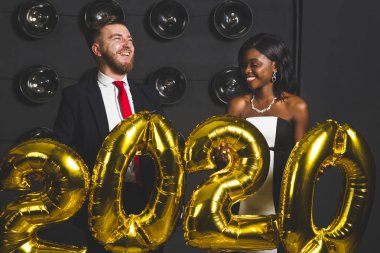 2020 yılındaki şirket partisinde balon tutan güzel genç insanlar. Mutlu yeni yıl kutlamaları. Arkadaşlarla kulüp partisi.