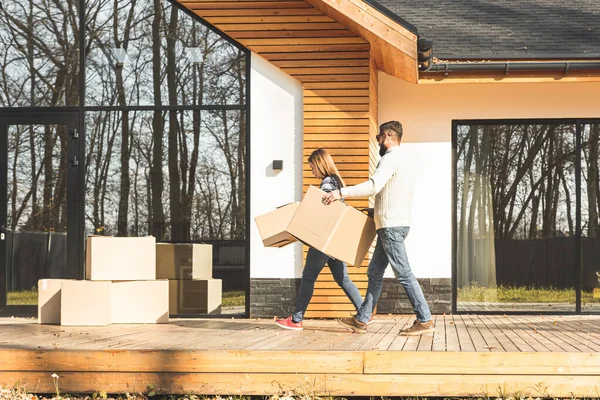 Giovane coppia si trasferisce in una nuova casa. la famiglia porta scatole di cose dopo l'acquisto di una casa . — Foto Stock