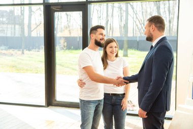 Emlakçı genç bir çifte yeni bir ev gösteriyor. Aile konut satın alır