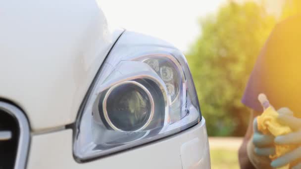 Autótisztítás. Egy kesztyűs férfi letörli egy autó fényszóróját egy speciális ronggyal.. — Stock videók