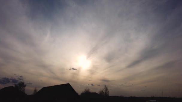 Timelapse dinámico el sol se pone en las nubes sobre el fondo de siluetas de casas rurales privadas — Vídeo de stock