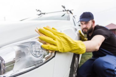 Temizlik servisi. Üniformalı ve sarı eldivenli bir adam araba yıkamada araba yıkar.