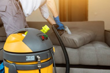 Kuru temizlemeci çalışanı mobilyalardaki toprağı temizliyor, yakın plan, elektrikli süpürge, profesyonel ekipman ile temizliyor.