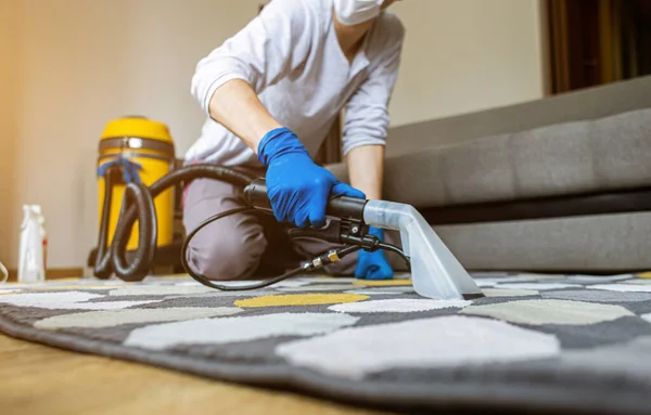 Lavanderias homem empregado homem remoção de sujeira do tapete, vácuo limpo com equipamento profissional . — Fotografia de Stock