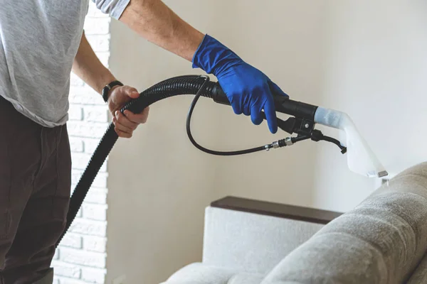 Närbild man hand i skyddande gummihandske rengöring soffa med professionellt extraktion metod. Tidig vårstädning. Kommersiell städfirma — Stockfoto