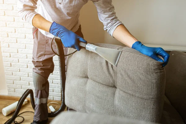 Stomerij man werknemer het verwijderen van vuil uit meubels in flat, close-up, stofzuigen bank met professionele apparatuur. schoonmaakdienst. — Stockfoto