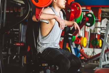 Genç sporcu spor salonunda egzersiz yapar. Simülatörde güç yaklaşıyor.