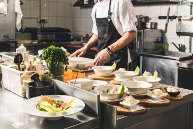 Oteldeki mutfak restoranında yemek pişiren profesyonel bir aşçı. Yemek hazırlıyor. Önlüklü bir aşçı sebze ve pizzadan salata yapar..