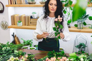 Çekici genç bayan çiçekçi bir çiçekçide çalışıyor..