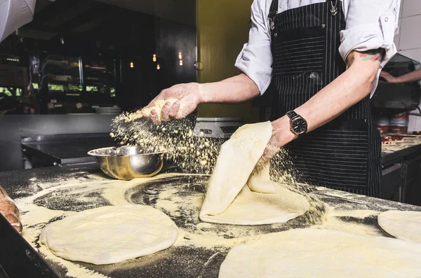 Professional chef cooking in the kitchen restaurant at the hotel, preparing dinner. A cook in an apron makes a salad of vegetables and pizza. — Stock Photo, Image