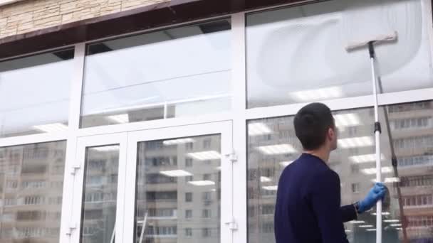 Een professionele glazenwasser zepen en piepen een raam schoon, mannelijke schoonmaakster. — Stockvideo